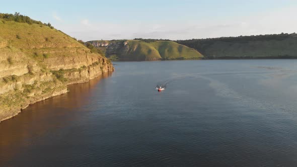 Aerial drone shot: motorboat floating the huge river along the bank.