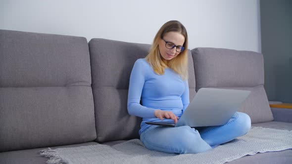 Freelancer writer working on modern notebook computer on couch at home in 4k alt