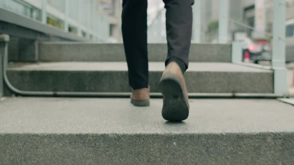 Close up legs of businessman walking on the street in the modern city.