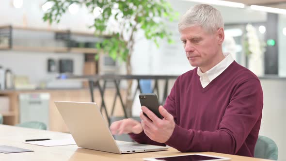 Middle Aged Man Using Laptop and Smartphone  alt