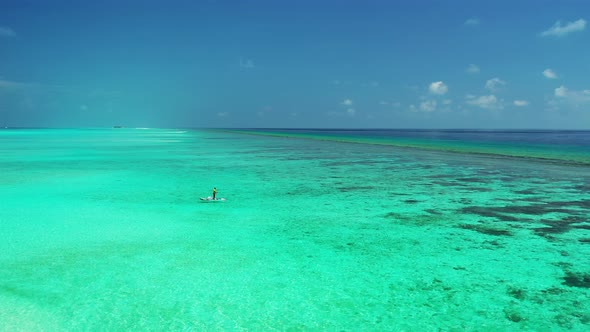 Local fisherman on the paddleboard throwing the fishing line in the calm sea, Maldives alt