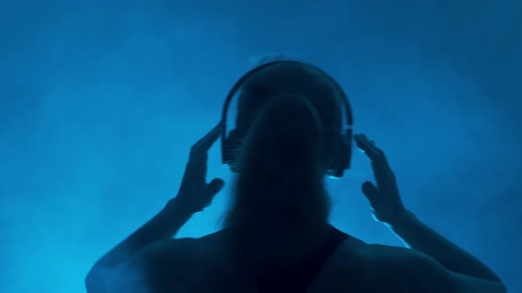 Silhouette of Female Dj in Headphones on Dark Background  alt