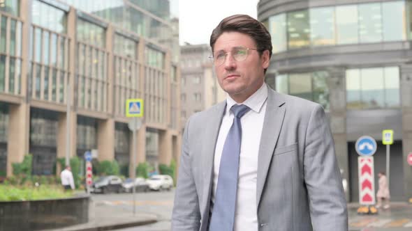 Middle Aged Businessman Walking on Street alt