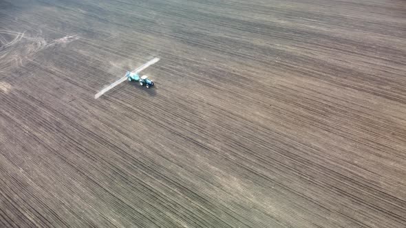 Fly around tractor spraying seeds on land field