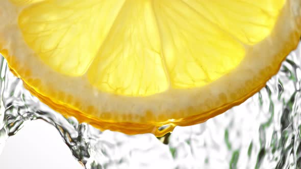 Super Slow Motion Macro Shot of Flowing Water From Lemon Slice on White Background at 1000Fps alt