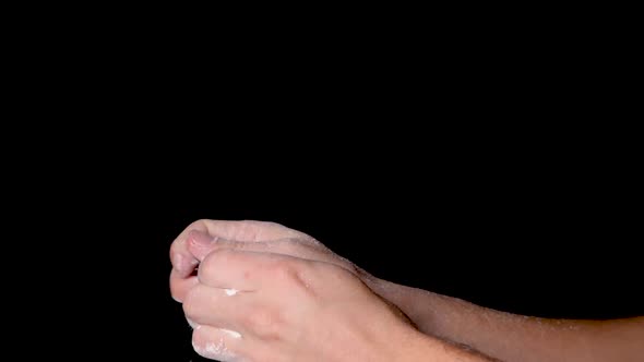 A person rubbing his hands and evenly distributing the chalk powder, isolated on black background. S alt