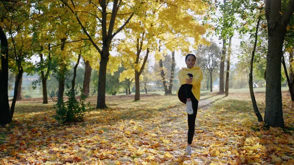 Girl Exercising and Stretching Before Morning Run at the Park in Autumn alt
