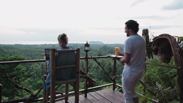 Freelancer woman sits with a laptop on a high bar chair. alt
