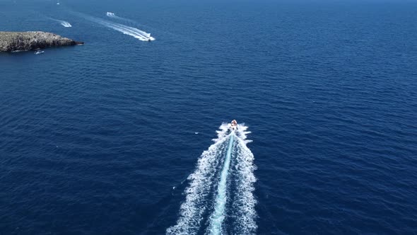 Speedboats trailing in blue waters of Polignano a mar, Italy. Aerial rising alt