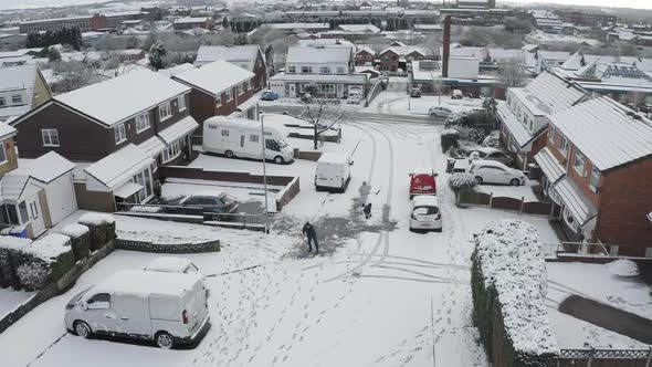 A family scrape snow and ice from their driveway and the road after a heavy snowfall, blizzard in th alt