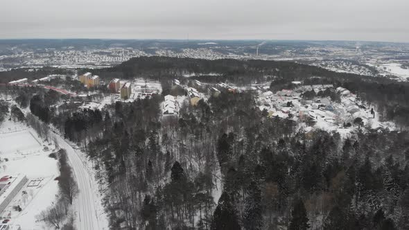 Residential Area on Hilly Forest Covered with Snow Long Shot Aerial