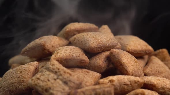 Hot crispy chocolate pads with smoke rotate on a black background. Cocoa cereal dessert alt