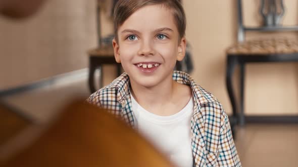 Caucasian boy sitting opposite his father and singing a song