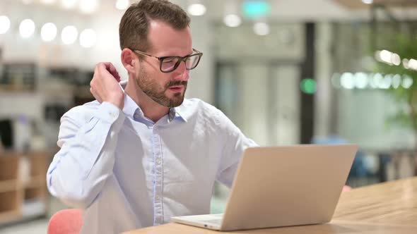 Tired Businessman with Laptop Having Neck Pain in Office alt