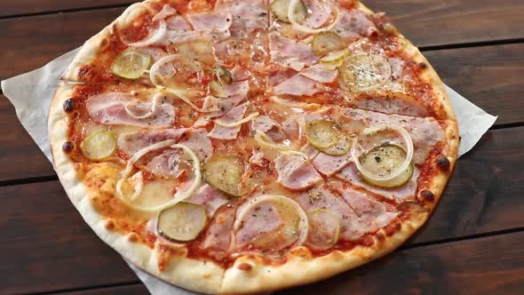round pizza with mozzarella cheese, salami, cucumber and onion, rotating close-up