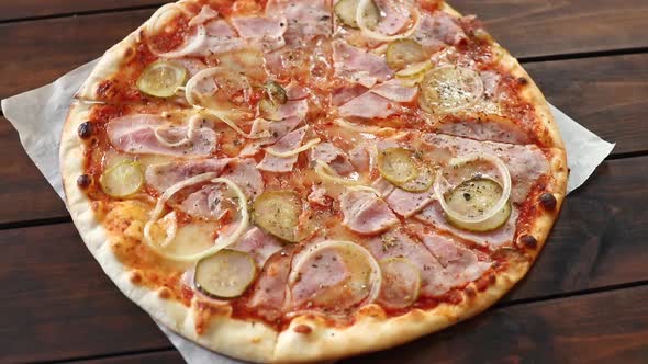 round pizza with mozzarella cheese, salami, cucumber and onion, rotating close-up alt