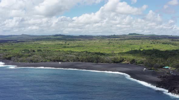 Descending close-up aerial shot of a brand new black sand beach on the Big Island of Hawaii. 4K alt