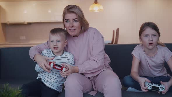 Woman and Kids Playing at Video Game Using Controller