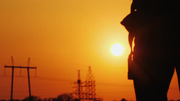 Tourist with a Backpack Goes Forward To the Big Setting Sun and the City Ahead. Against a Beautiful alt