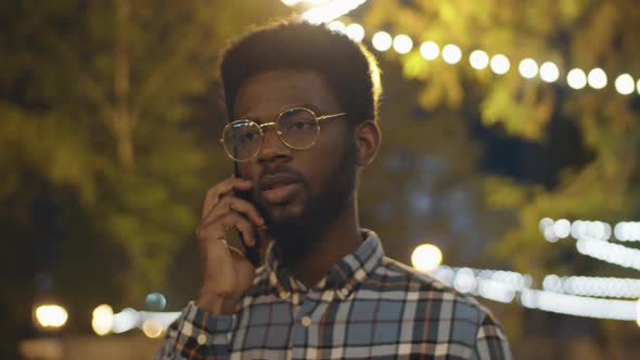 Black Man Talking on Phone Outdoors in Evening alt