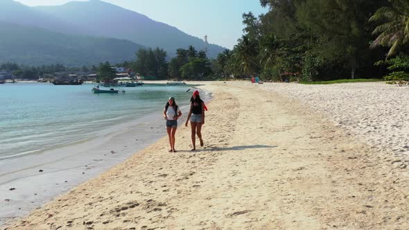 Girls relaxing on marine seashore beach time by blue ocean with white sand background of Koh Phangan alt