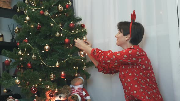 Happy charming woman is hanging ball on a Christmas tree, decorating Christmas tree, New year alt