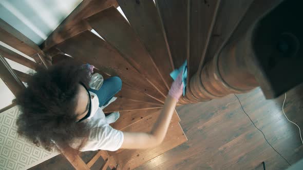 A Girl Cleans Stairs with Sanitizer to Prevent Coronavirus Spread alt