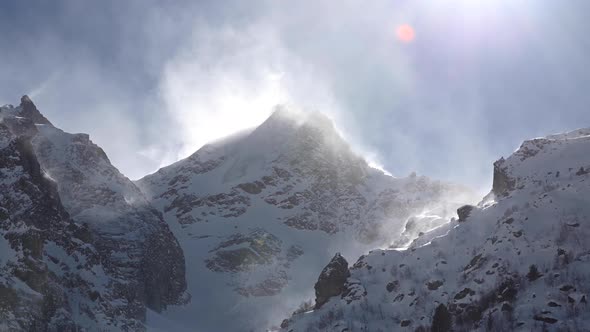 Timelapse on a Telephoto Lens of Snowcapped Peaks of High Mountains with Snow Blowing From the Peaks alt