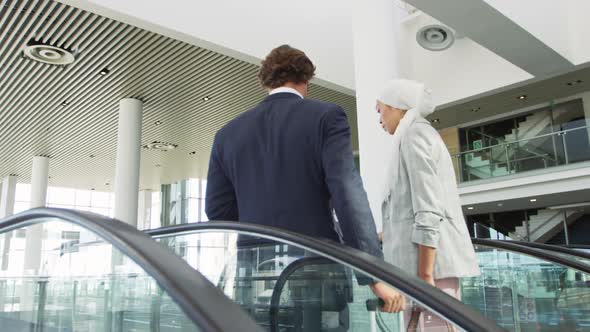 Young business people on an escalator in a modern building alt