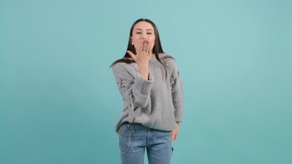 Beautiful Young Woman Looking at the Camera Blowing a Kiss with Hand on Air