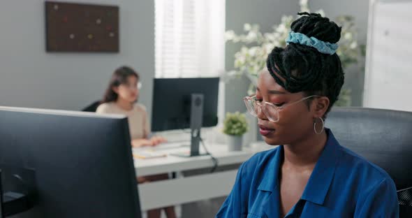 Polite Elegant Customer Service Representative in Large Corporation Sits at Computer Tapping Fingers alt