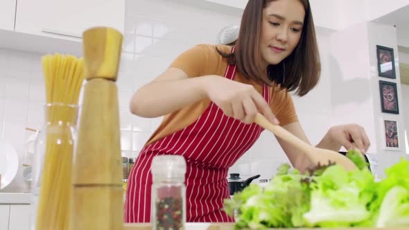 Young Asian woman cooking in kitchen at home. alt