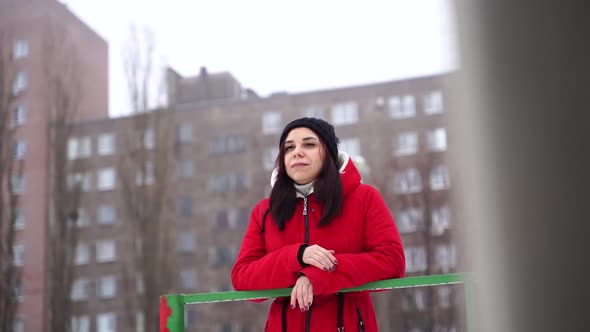 Young Woman in Hat and Red Jacket Standing on Street alt