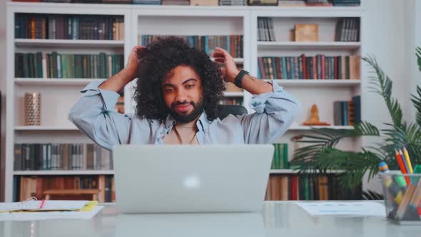 Young Middle Eastern Man Leans Back in Chair After Hard Days in Office alt