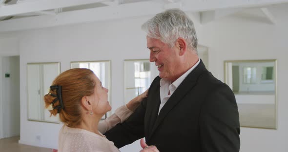 Caucasian senior couple spending time together dancing in a ballroom alt