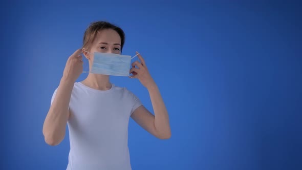 Slow Motion: Woman Putting on Medical Face Mask and Looking at Camera at Home