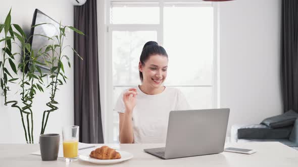 A happy woman using her laptop while talking with video connection alt