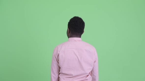Rear View of Young African Businessman Pointing Finger alt