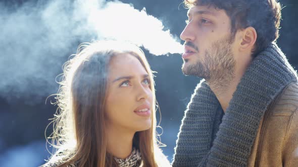 Woman looking at her boyfriend smoking alt