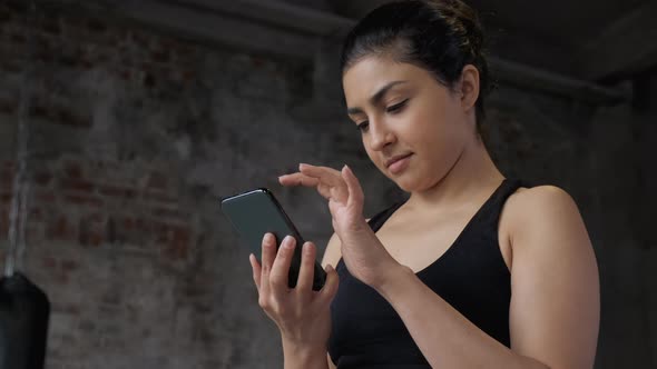 Sweat woman using mobile phone after workout. Woman preparing for workout using fitness app alt