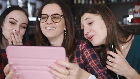 Fun Girl Talk at the Table in the Restaurant and Viewing Photos on the Tablet alt