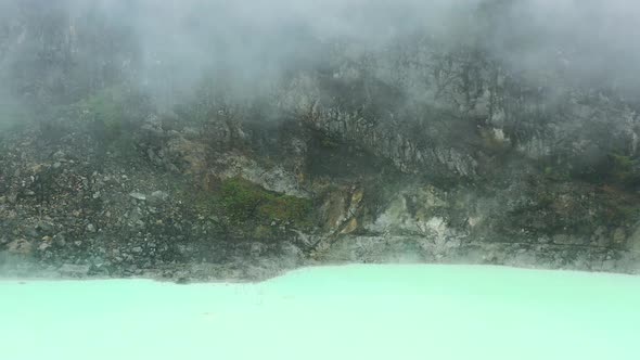 rocky mountain landscape at crater rim of Kawah Putih with neon water shoreline alt