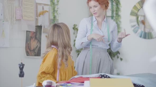 Red-haired Mother and Her Daughter Admiring a Piece of Beautiful Fabric alt