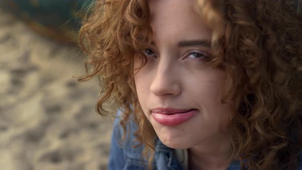Playful Woman Blowing Curls From Face Sitting Beach Near Old Boat Close Up alt