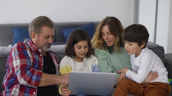 Grandfather with Two Grandchildren and Daughter Making Video Call Using Laptop alt