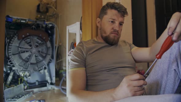 Middleaged Man Tired of Repairing His Home Washing Machine on His Own