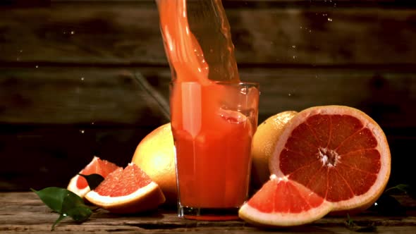 Super Slow Motion in a Glass with Grapefruit Juice Falls a Piece of Grapefruit with Spray alt