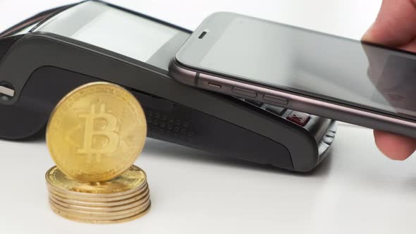 Close Up Man Hand Contactless Paying By Smartphone and Bitcoin Coins on the Table alt