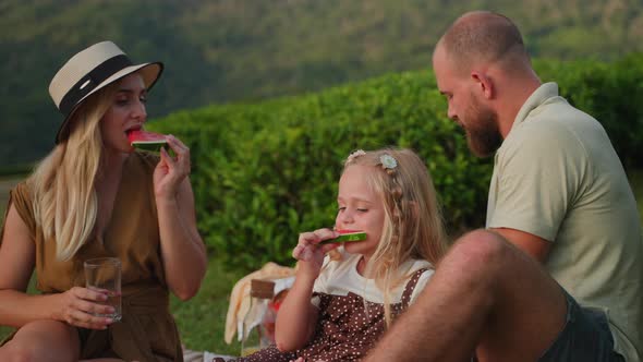 Picnic of Happy Family in Summer Weekend Woman Her Husband and Daughter are Eating Watermelon alt