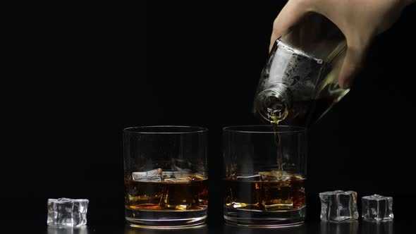 Pouring Whiskey, Cognac Into Glass. Black Background. Pour of Alcohol Drink alt